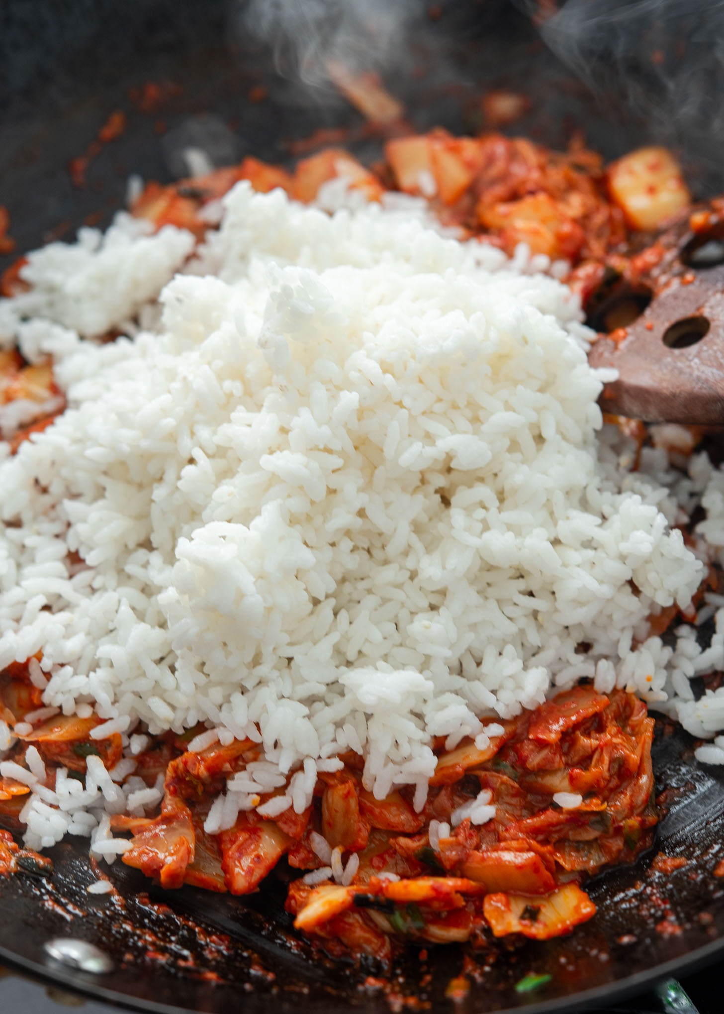 Cold rice added to stir-fried kimchi in the skillet