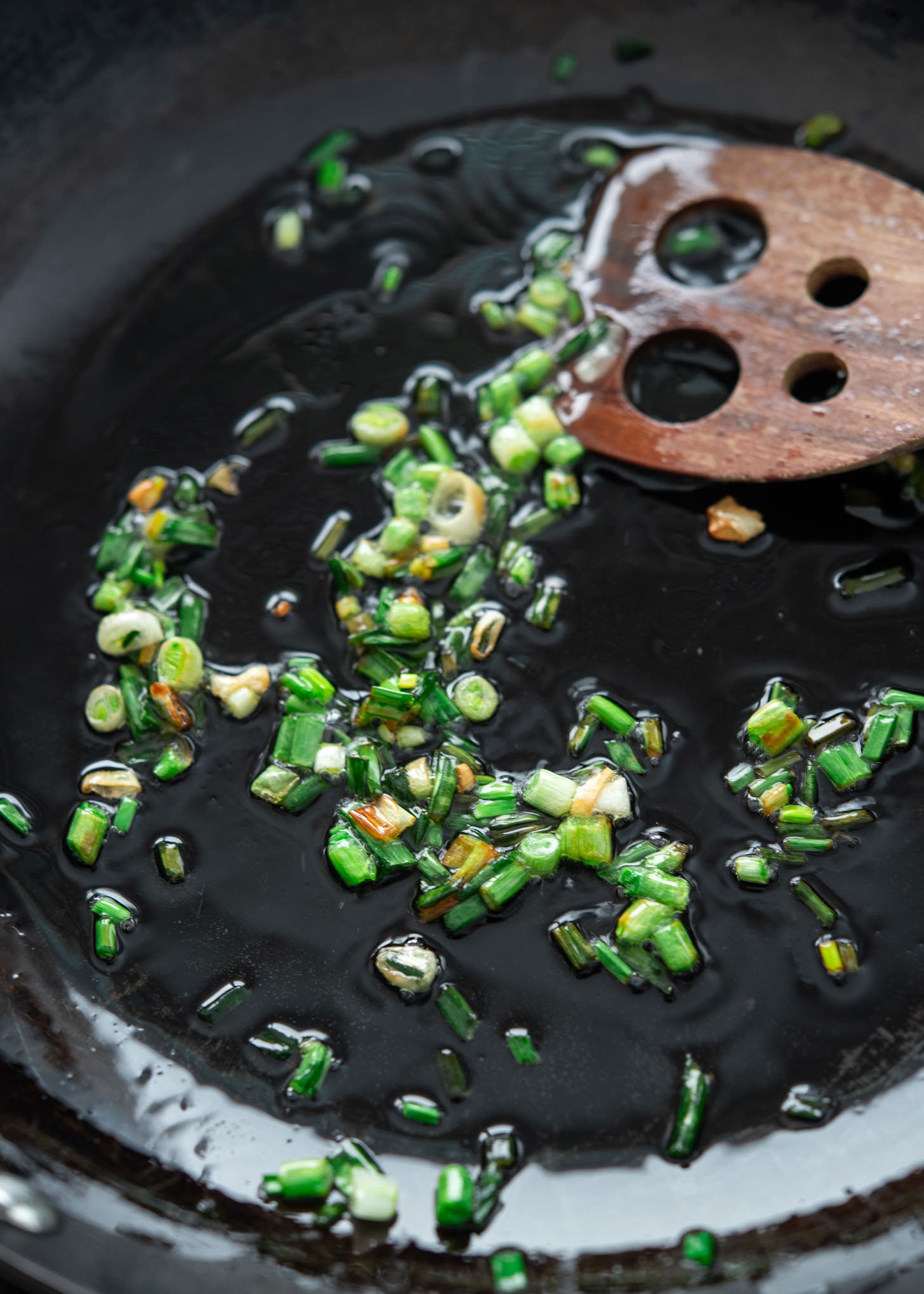 Infusing sliced green onion in hot oil in a skillet