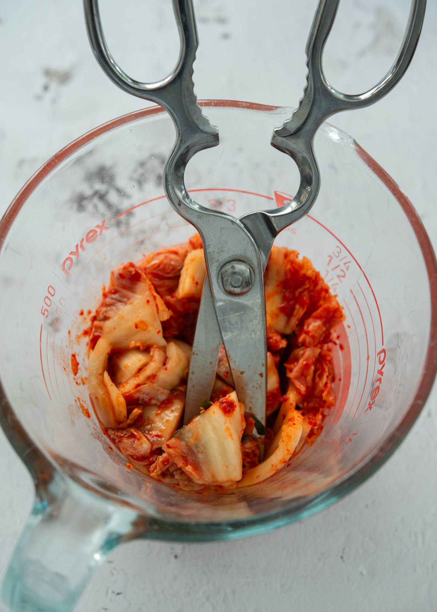 Chopping kimchi into bite-size pieces with kitchen scissors