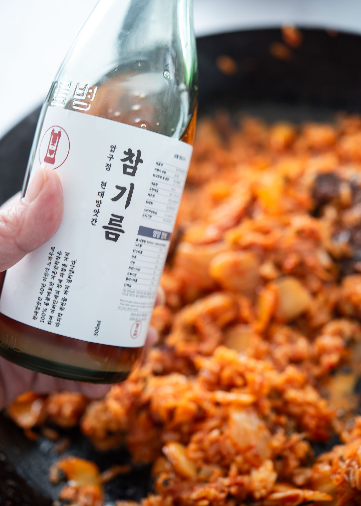 Adding sesame oil to finish kimchi fried rice
