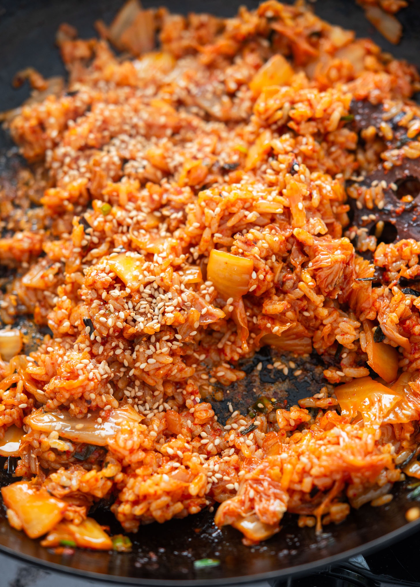 Sprinkling toasted sesame seeds over kimchi bokkeumbap