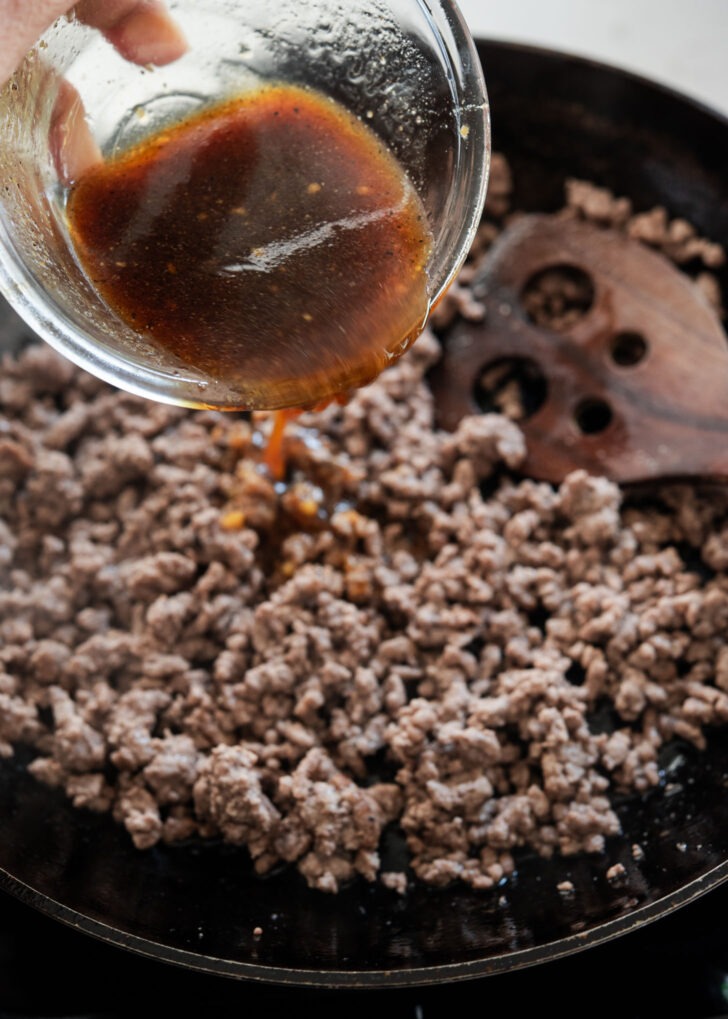 Bulgogi sauce poured over browned ground beef in a pan