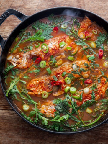 Korean fish stew (maeuntang) with croaker, radish, and fresh herbs in a spicy red broth
