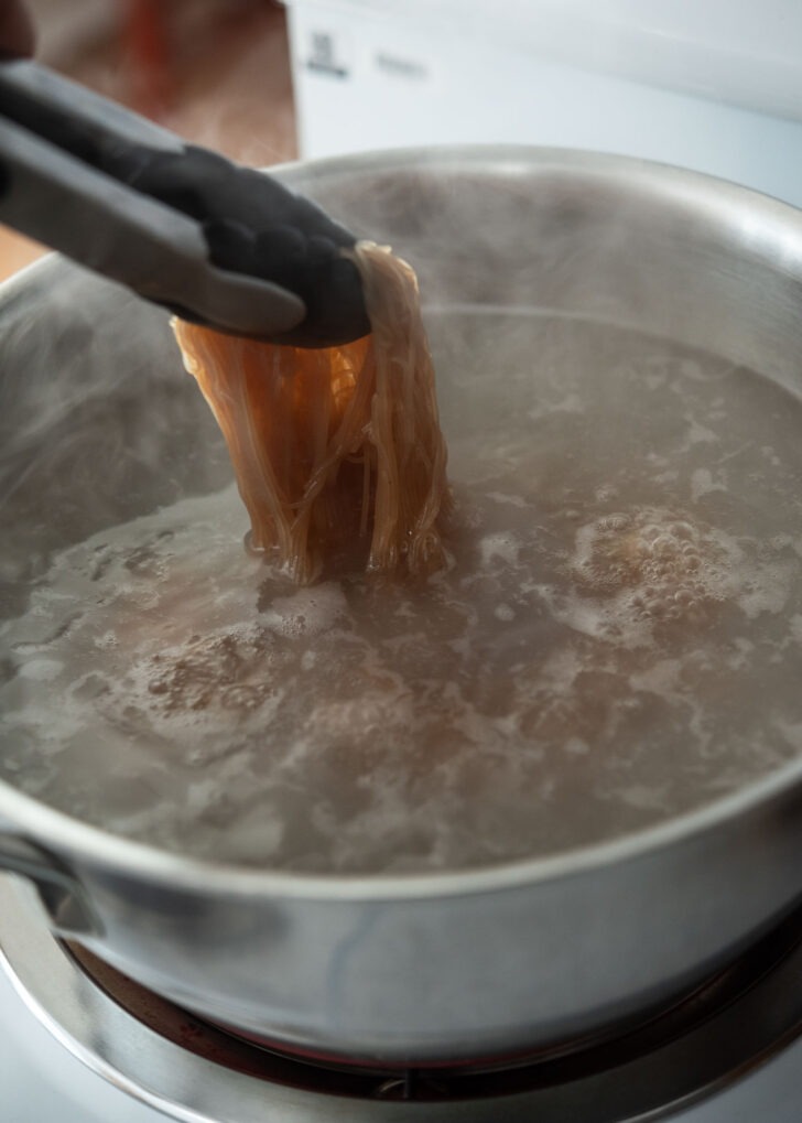 Cooking naengmyeon noodles in a pot of boiling water