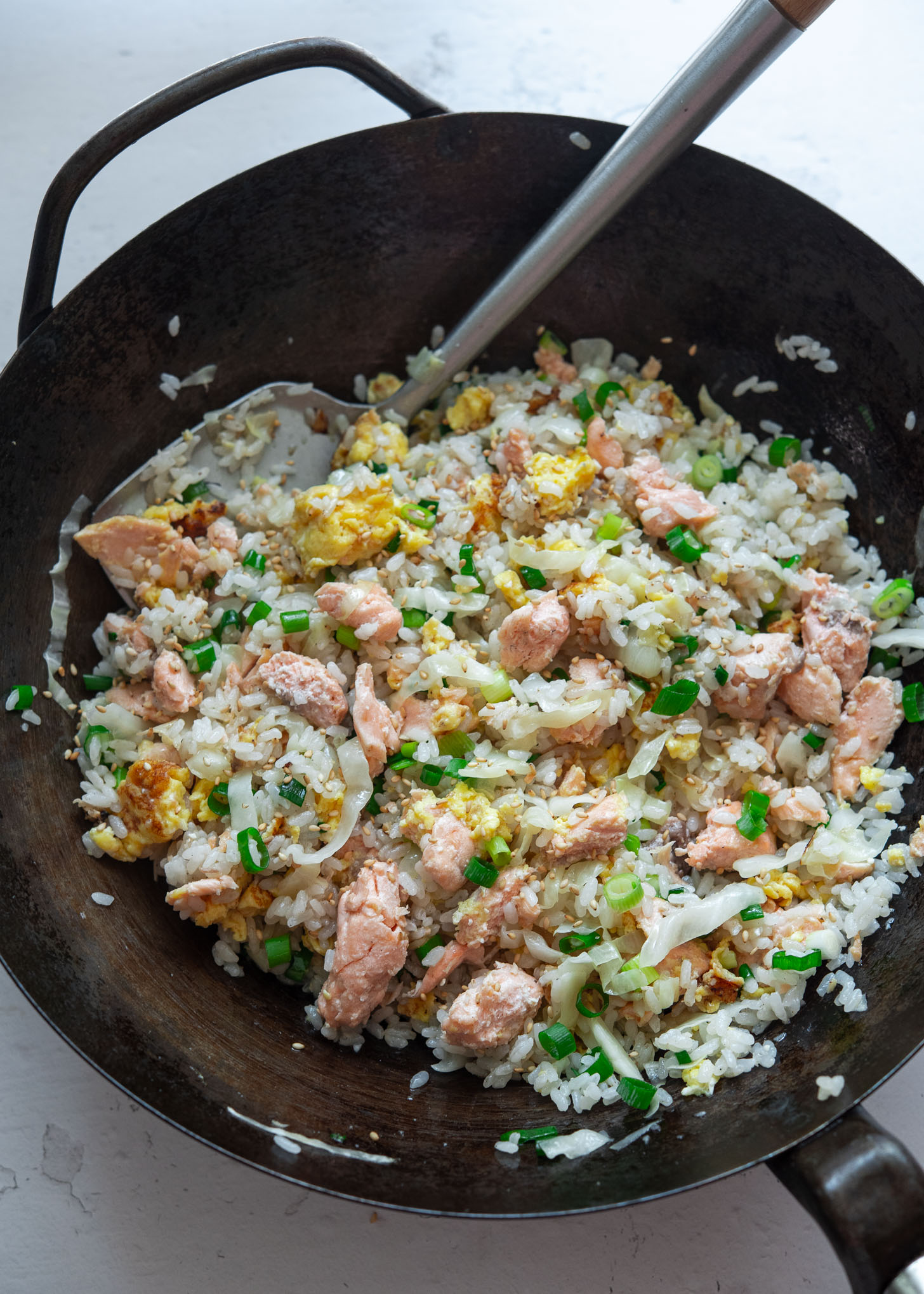 Salmon fried rice with fluffy egg shown in a wok