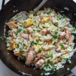 Salmon fried rice with egg shown in a wok