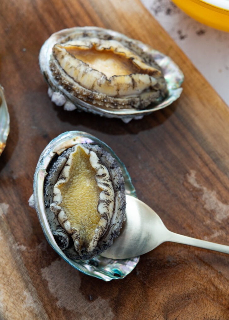 Sliding a spoon between the shell and flesh part of abalone