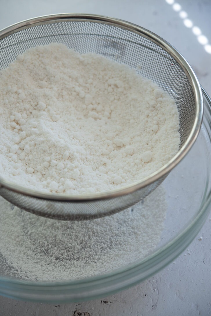 Sifting moistened rice flour through a sieve