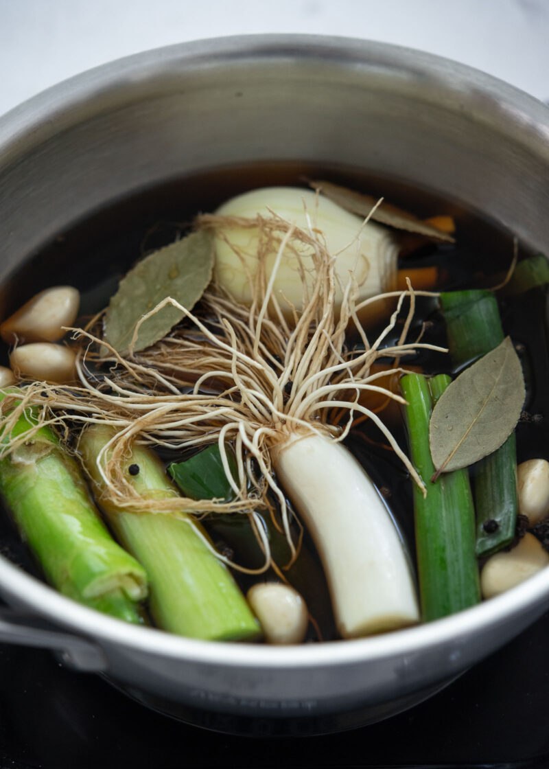 Soy marinade with onion, garlic, daepa roots, and bay leaves in a pot.