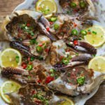 Ganjang gejang soy-marinated crab with lemon slices, green onions, and chilies.