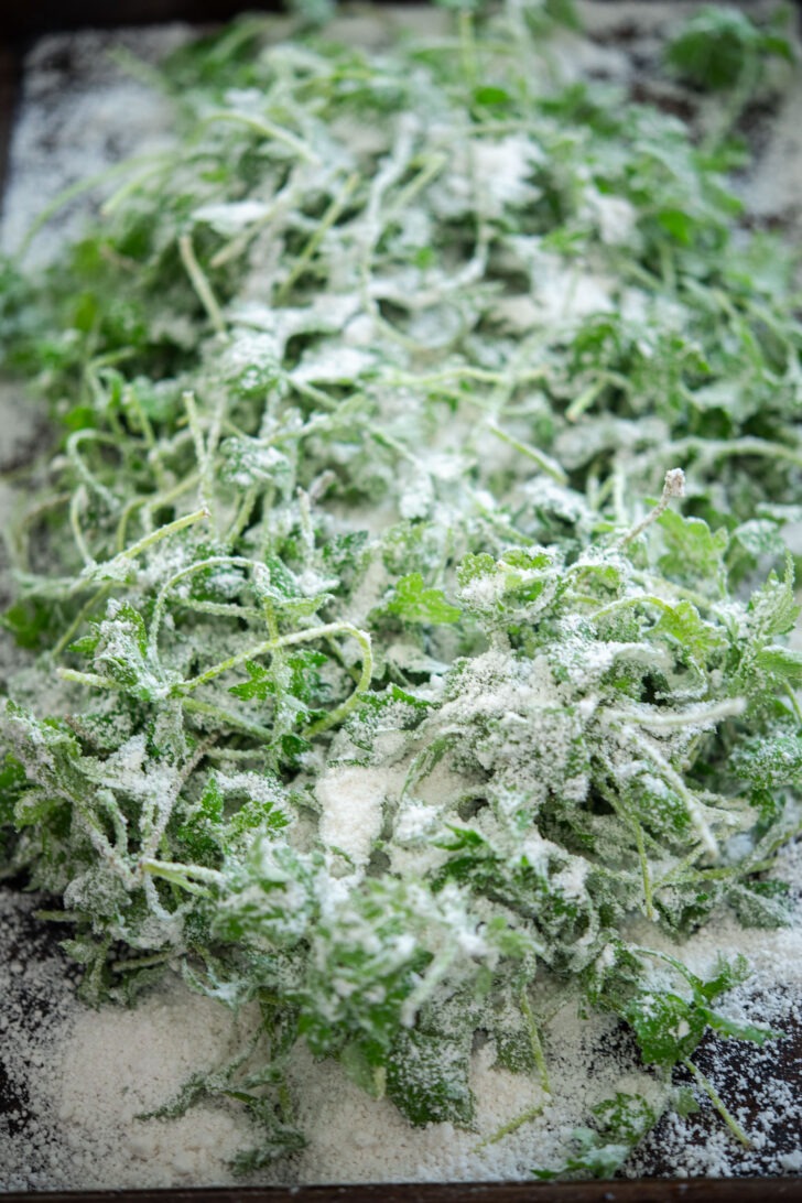 Coating moist mugwort with rice flour mixture on a baking sheet