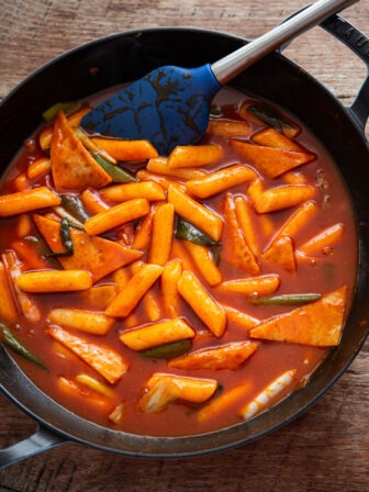 Tteokbokki, Korean spicy rice cakes, simmered in glossy red gochujang sauce in a skillet