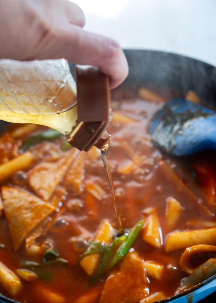 Drizzling Korean oligo syrup into tteokbokki for glossy finish