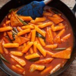 Tteokbokki, Korean spicy rice cakes, simmered in glossy red gochujang sauce in a skillet