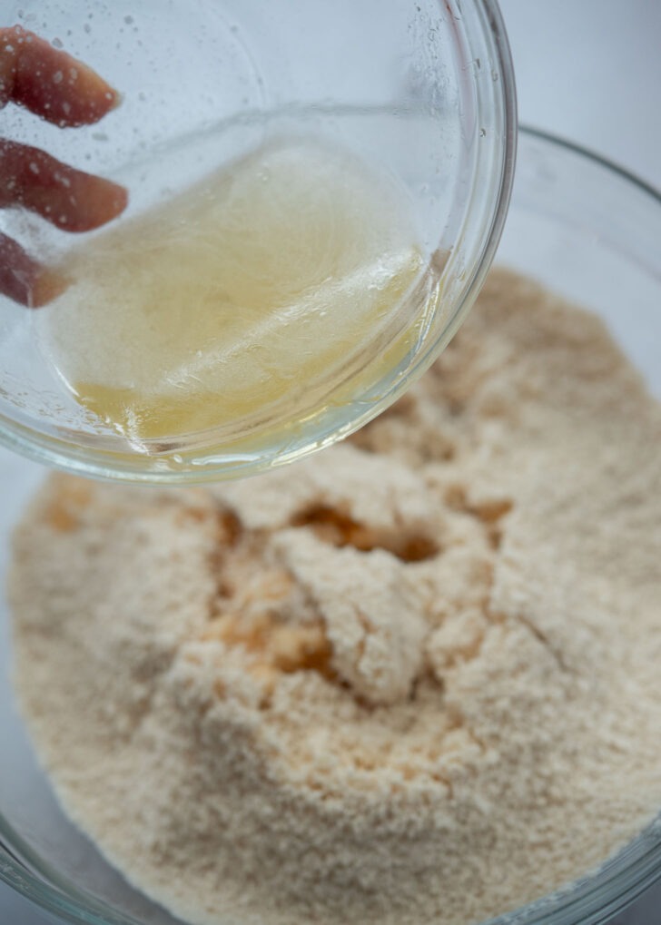 Pouring the honey, sugar, salt, and water mixture into the flour