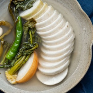 Dongchimi served in clear chilled brine with sliced Korean radish and greens