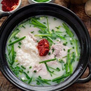 dwaeji gukbap Korean pork rice soup with pork slices, garlic chives, and dadaegi chili topping