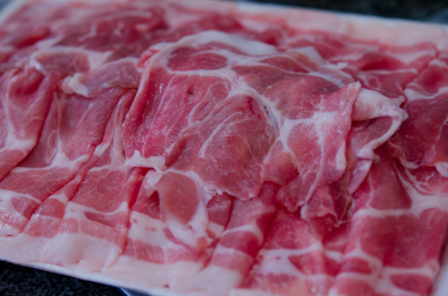 Thinly sliced pork shoulder is showing some marbled pattern in the meat.
