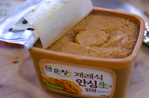 A container of Korean soybean paste (doenjang) is shown.