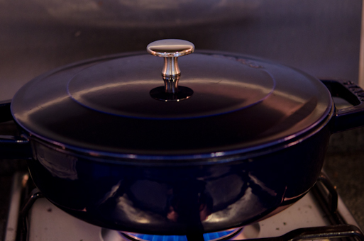 A pot covered with a lid is placed on the stove.