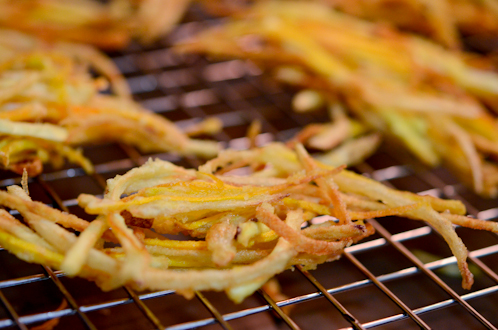 Root vegetable tempura is resting on a wired rack