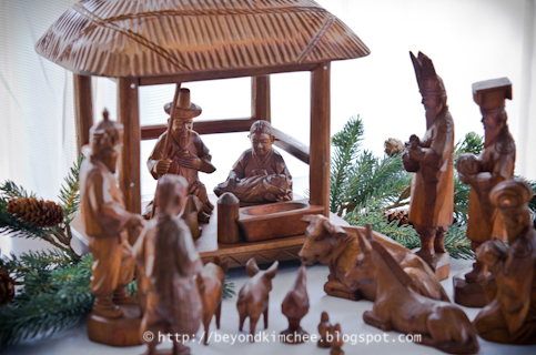 Korean wooden Nativity set is displayed with some greenery.