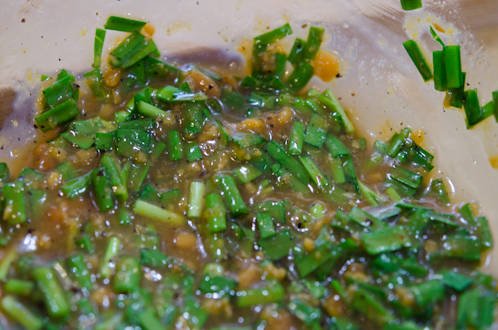 Chopped Asian leek pieces are added to doenjang marinade in a bowl.