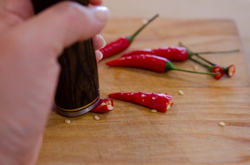 Back of a knife pounding red chili.