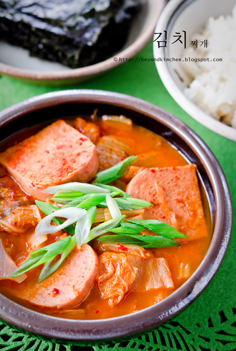 Kimchee jjigae made with slices of Spam are garnished with green onion and served with rice.